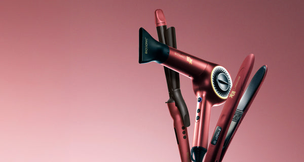 Bio Ionic Velvet Rouge collection: metallic red 10X Dryer, Long Barrel Curling Iron, and 10X Styling Iron against pink background.