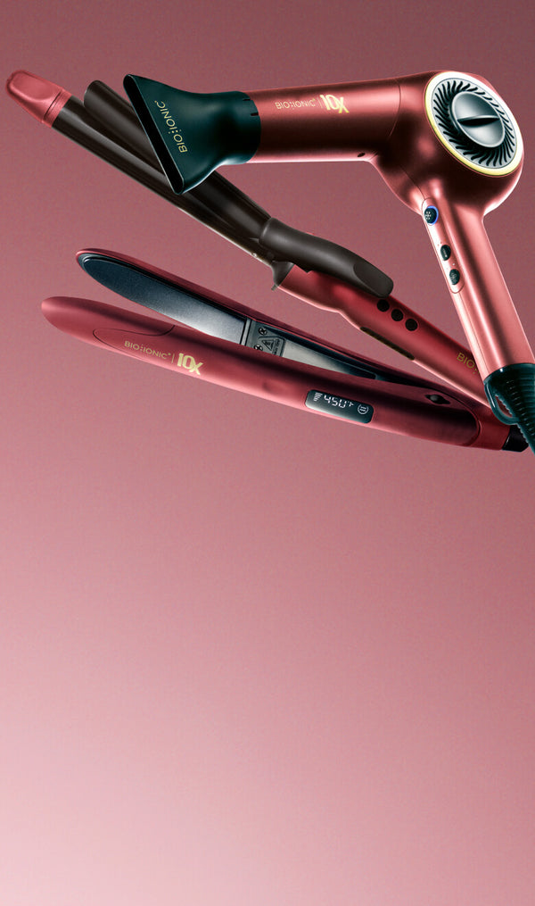 Bio Ionic Velvet Rouge collection: metallic red 10X Dryer, Long Barrel Curling Iron, and 10X Styling Iron against pink background.
